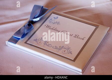 A wedding guest book with a blue ribbon on a white table cloth. Stock Photo