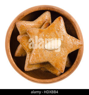 Gingerbread stars in wooden bowl. Sweet baked goods. Brown, flat and star-shaped with an almond half on top. Stock Photo