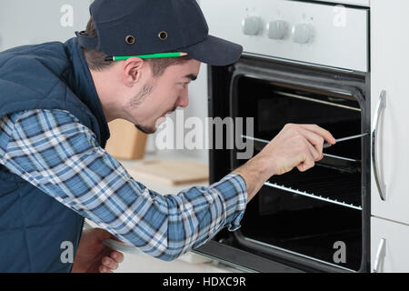 young repairman in overall installing brand new oven in kitchen Stock Photo