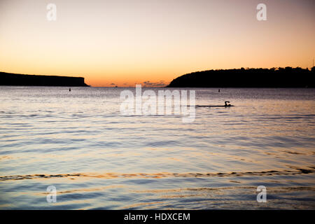 Arm of a swimmer comes out of the water mid-stroke swimming in the sea before sunrise Stock Photo