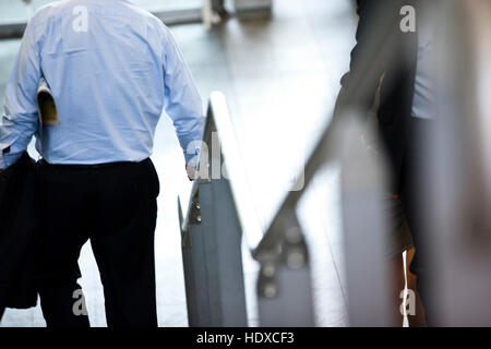 A business man holds handrail walking down steps on way to work Stock Photo