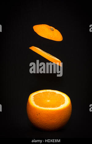 Levitating fresh sliced fruit, orange isolated on black background. Healthy food. Stock Photo
