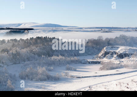 A wintry scene: looking over Walltown Quarry from Walltown Crags, with snow on the ground and low-lying mist in the hollows Stock Photo