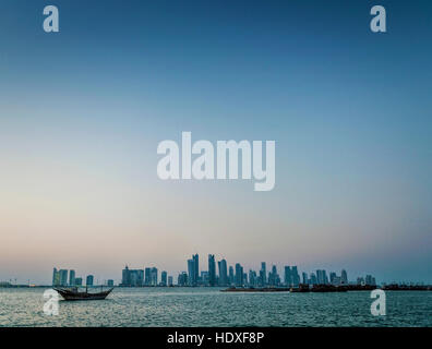 doha city skyscrapers urban skyline view and dhow boat in qatar at sunset Stock Photo