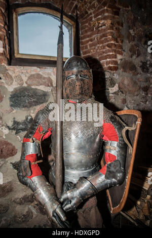 Medieval warrior soldier metal protective wear. suit of knight armour stand inside tample interior with window in  brick wall Stock Photo
