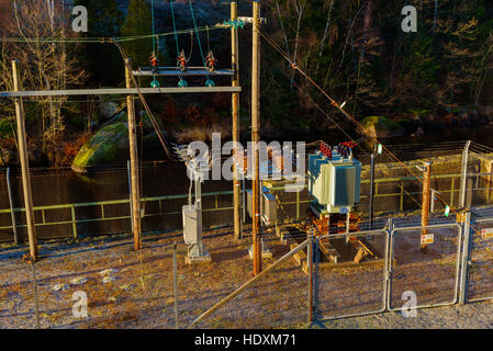 Brantafors, Sweden - December 14, 2016: Documentary of local power grid. Small power substation with a river in the background. Barbed wire fencing su Stock Photo