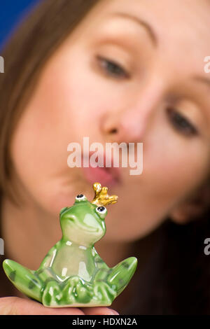 Woman kissing a frog prince Stock Photo