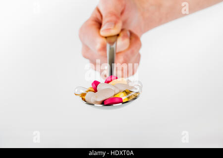 Pile of pills in spoon on white background Stock Photo