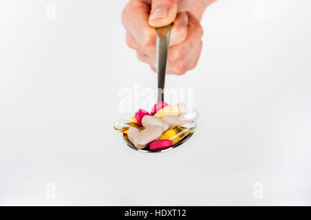 Pile of pills in spoon on white background Stock Photo