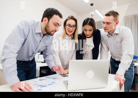 Brainstorm. Group of cheerful business people in smart casual wear looking at the laptop together and smiling Stock Photo