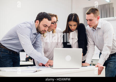 Brainstorm. Group of cheerful business people in smart casual wear looking at the laptop together and smiling Stock Photo
