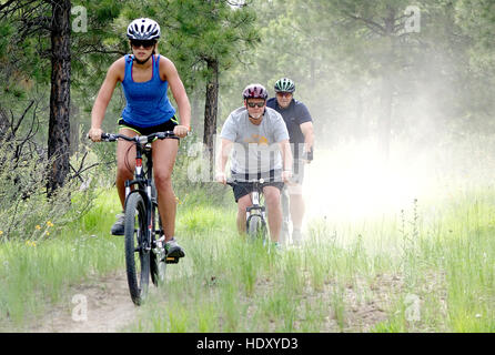Three mountain bikers on a dusty trail. Stock Photo