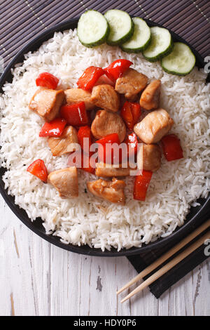 Rice with chicken pieces in a sauce on a plate close-up. vertical top view Stock Photo