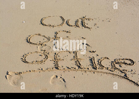 Out of office text written in sand on a beach suggesting work life balance Stock Photo