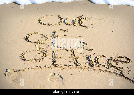 Out of office text written in sand on a beach suggesting work life balance Stock Photo