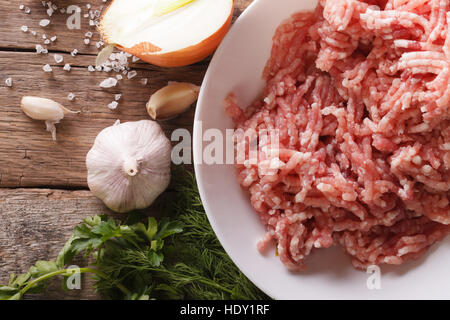 Raw minced meat and ingredients on the table. horizontal view from above, rustic style Stock Photo
