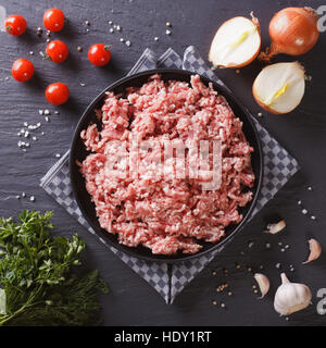 Raw minced pork in a plate and fresh vegetables on a table close-up. top view Stock Photo