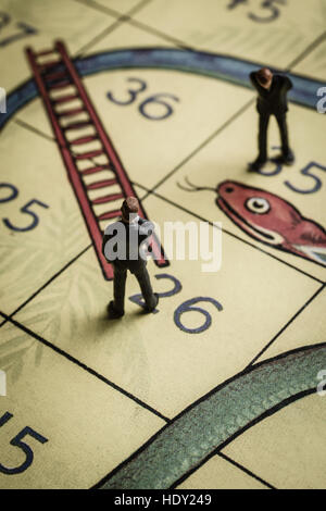 Business men pondering success and failure on a snakes and ladders board a problem solving concept Stock Photo