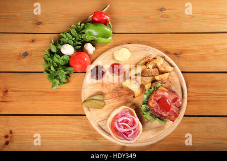 beef burger on a plate served with fried potatoes and sauces Stock Photo