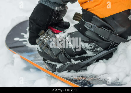 The man in black boots buttons fastening snowboard Stock Photo