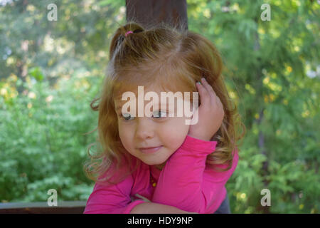 Cute little girl posing in the botanical garden on the sunny day Stock Photo