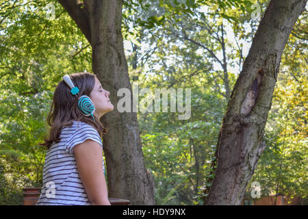 Girl listening to the music through headphones in the park Stock Photo