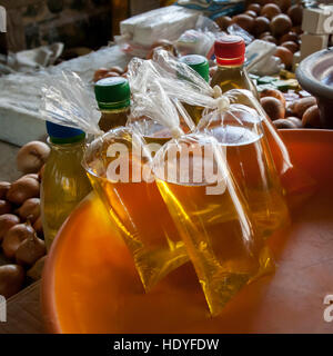 Golden-yellow palm oil sits in knotted plastic bags and bottles next to a pile of onions on a market stall in Tuala, Sierra Leone. Stock Photo