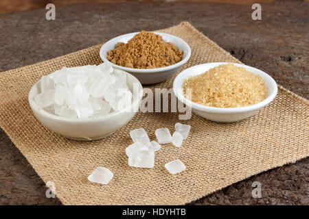 Brown cane sugar and granulated sugar and rock sugar in a cup on old wood. Stock Photo