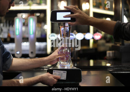 A demonstration takes place of the world's first contactless, self-serving beer pump developed by Barclaycard to help cut bar queues on nights out, at Henry's Cafe and Bar in Piccadilly, London. Stock Photo