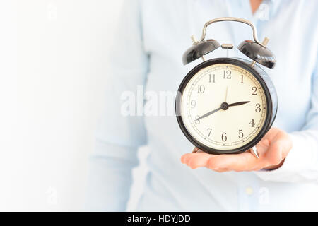 Businesswoman holding an old clock in hands suggesting deadline concept Stock Photo