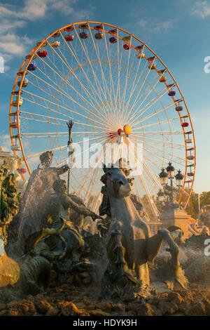 Bordeaux Fountain statues in front of Big Ferris Wheel at fun fair against a clear blue sky Stock Photo
