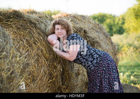 Beautiful pensive woman in field with straw bales Stock Photo