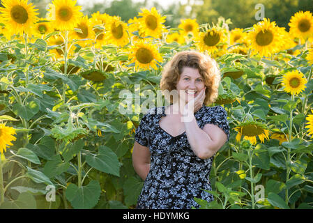 curly-haired woman in field of sunflowers Stock Photo