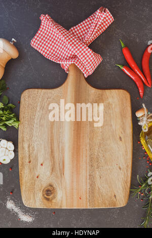 Empty wood cutting board with various fresh herbs and spices on dark background Stock Photo