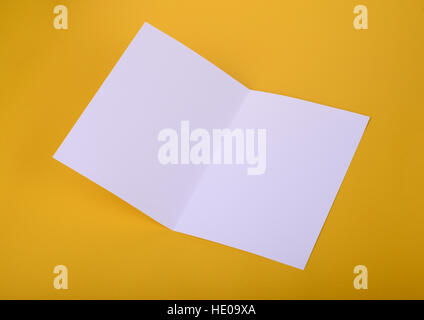 white paper bifold brochure mockup on yellow background Stock Photo