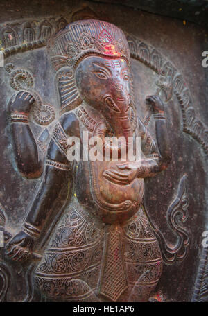 Bronze carving of Ganesh with red & yellow power paint on its head from blessings in the temple, Kathmandu, Nepal. Stock Photo