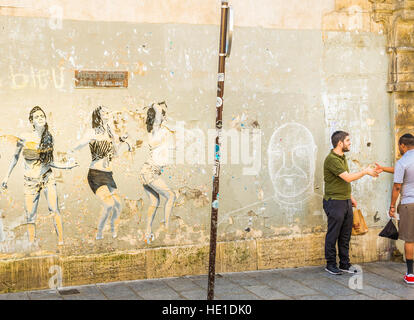 street scene in front of graffito showing dancing young people Stock Photo