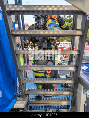 A firefighter starts up stairs on a four story tower carrying bundled hose. Stock Photo