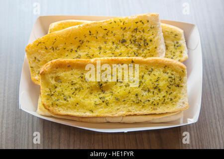 Close up of crunchy garlic baguette on the wooden table at daytime. Stock Photo