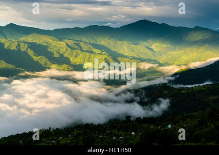 Fog is covering Phewa Lake in the morning, surrounding hills with trees are sunlit Stock Photo