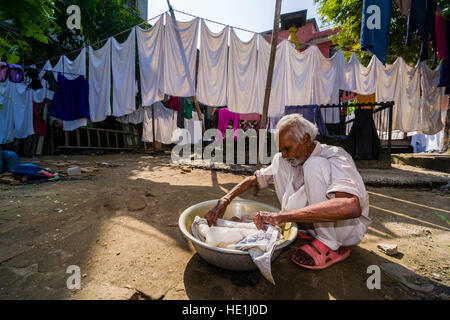 A man is doing laundry by hand in a courtyard Stock Photo