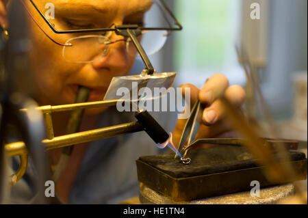 The Goldsmith working with an earring, solder a new pin Stock Photo - Alamy