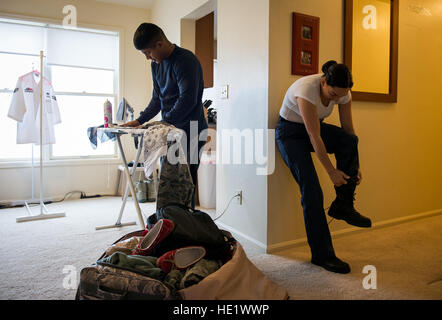 Airman 1st Class Ozzie Galvan left helps his wife, Airman 1st Class Alexandra Ayub, prepare for a four-day deployment by ironing and packing her clothes while she dresses at their home at Francis E. Warren Air Force Base, Wyoming. Ayub, a missile chef, regularly deploys to provide meals to the Airmen stationed at missile alert facilities that are many miles away from her home base. /Staff Sgt. Andrew Lee Stock Photo