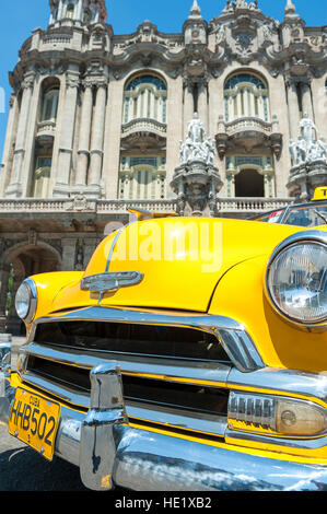 HAVANA, CUBA - JUNE 13, 2011: Bright yellow vintage American taxi car stands parked in front of the landmark Great Theater. Stock Photo
