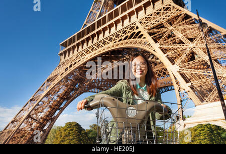 Pretty young woman riding bike near Eiffel Tower Stock Photo