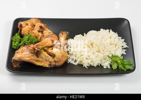 Grilled chicken thigh with rice and parsley on the table in natural light Stock Photo