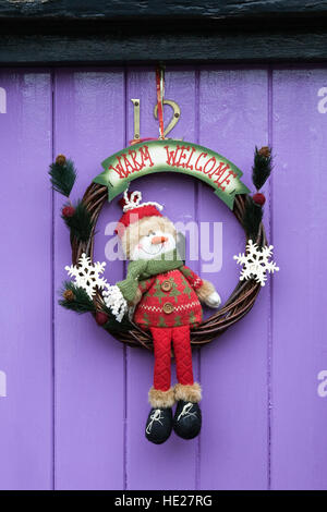 Decorative Christmas wreath hanging on a purple front door. Stock Photo
