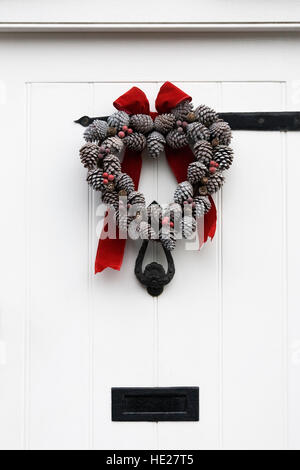 Decorative Christmas wreath hanging on a white front door. Stock Photo