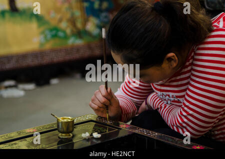 Factory worker painting furniture souvenirs in Xian, China. Stock Photo