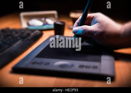 Graphic designer holding a pen over tablet. Stock Photo